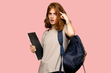Genç redhead öğrenci parmak pembe arka plan üzerinde kafasına koyarak delilik jest yapma