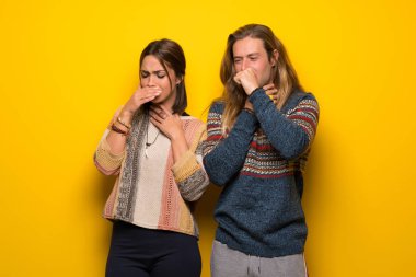 Hippi çift sarı arka plan üzerinde öksürük ile acı ve kötü hissediyor