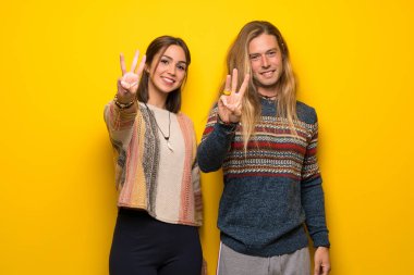 Hippi çift sarı üzerinde mutlu ve sayım üç parmak ile arka plan