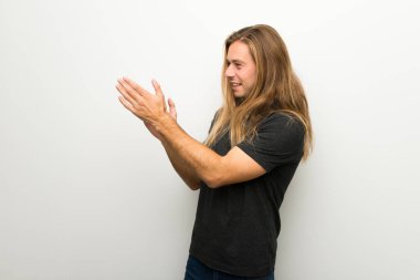 Bir konferansta sunum sonrası beyaz duvar alkış üzerinde uzun saçlı sarışın adam