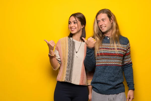 Hippi çift ürün sunmak için tarafına işaret sarı arka plan üzerinde