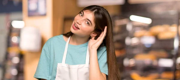 Chica Con Delantal Escuchando Algo Poniendo Mano Oreja Una Panadería — Foto de Stock