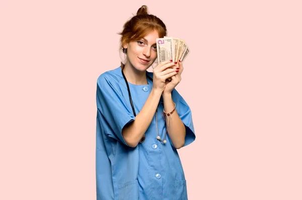 Joven Enfermera Pelirroja Tomando Montón Dinero Sobre Fondo Rosa — Foto de Stock