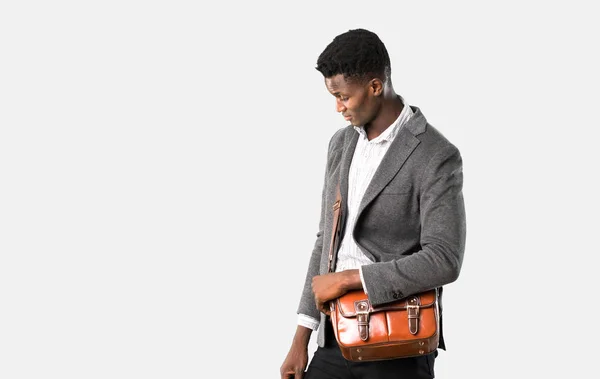 立っていると孤立した灰色の背景を見下ろしてのスーツケースと一緒に旅行アフリカ系アメリカ人のビジネスマン — ストック写真