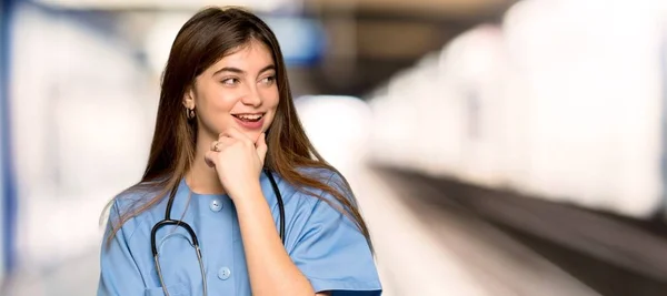 Jovem Enfermeira Olhando Para Lado Com Mão Queixo Hospital — Fotografia de Stock