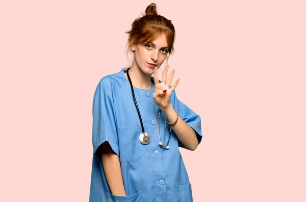 Молода Руда Медсестра Щаслива Рахує Чотири Пальці Рожевому Фоні — стокове фото