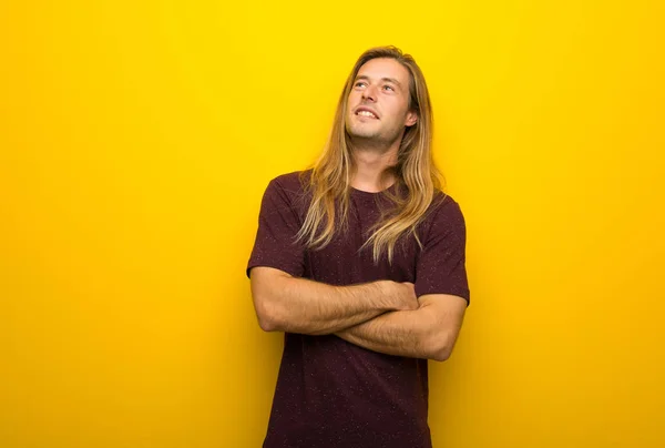 Hombre Rubio Con Pelo Largo Sobre Pared Amarilla Mirando Hacia — Foto de Stock