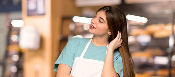 Girl with apron thinking an idea while scratching head in a bakery