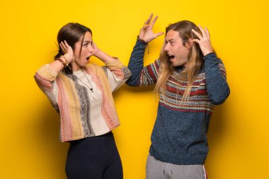 Hippi çift sürpriz ve şok yüz ifadesi ile sarı arka plan üzerinde