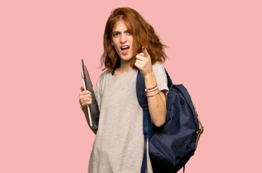 Genç redhead öğrenci kötü bir durum ve önüne pembe arka plan üzerinde göstererek sinirli