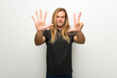 Beyaz duvar sekiz parmak ile sayma üzerinde uzun saçlı sarışın adam