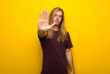 Yanlış düşünüyor bir durum inkar durdurmak jest yaparak sarı duvarın üzerinden uzun saçlı sarışın adam