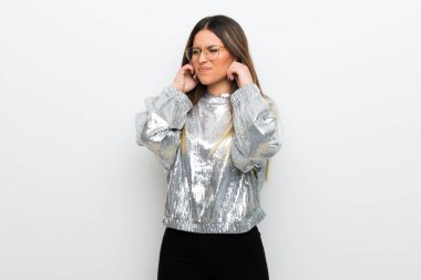 Beyaz duvar eller kulaklar kaplama üzerinde gözlüklü genç kadın. Hayal kırıklığı ifade