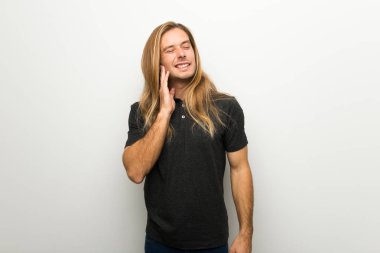 Diş ağrısı ile beyaz duvarın üzerinden uzun saçlı sarışın adam