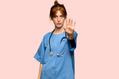 Pembe arka plan üzerinde yanlış düşünüyor bir durum inkar durdurmak jest yapma genç redhead hemşire