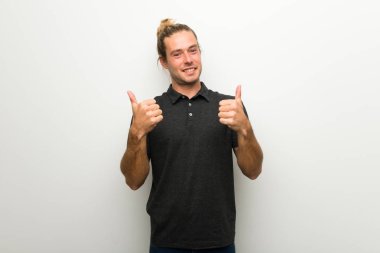 Her iki el ile jest Yaşasın vererek ve gülümseyen beyaz duvarın üzerinden uzun saçlı sarışın adam