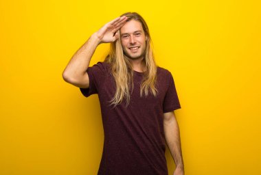 Sarı duvar el ile selamlayan üzerinde uzun saçlı sarışın adam