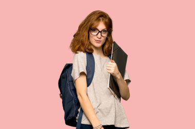 Genç redhead öğrenci ile gözlük ve pembe arka plan üzerinde gülümseyen