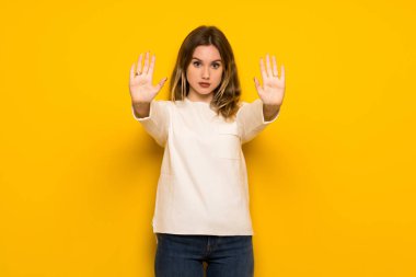 Genç kız dur jest yapmak için sarı duvarın üzerinden bir görüş ile hayal kırıklığına