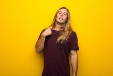 Yorgun ve hasta ifade ile sarı duvarın üzerinden uzun saçlı sarışın adam