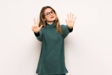 Genç kız beyaz duvar sekiz parmak ile sayma üzerinde