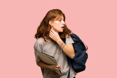 Bir şey üzerinde pembe arka plan kulak el koyarak dinleme genç redhead öğrenci