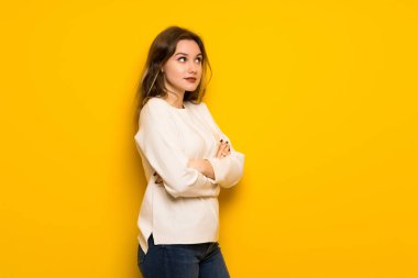 Genç kız üzerinde omuz kaldırma sırasında sarı duvar yapım şüpheler jest