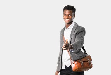 Afrika kökenli Amerikalı iş adamı ile izole gri arka plan üzerinde iyi bir anlaşma kapanış tokalaşırken bavul seyahat