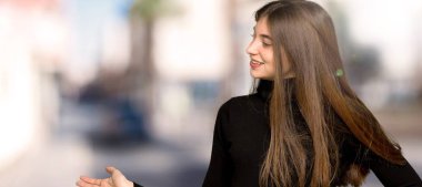 Geri işaret ve açık havada bir ürün sunma güzel kız