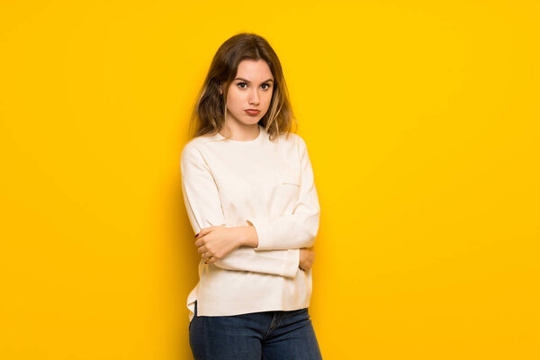 Подросток на желтой стене с грустным и депрессивным выражением лица
