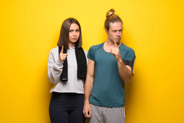 Group of athletes over yellow background frustrated by a bad situation and pointing to the front