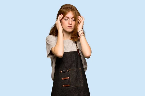 エプロン不幸と青い背景上のものに不満を持つ若い赤毛の女性 — ストック写真