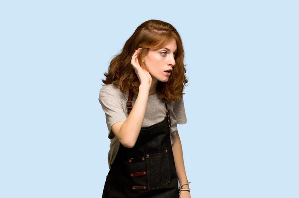 Young Redhead Woman Apron Listening Something Putting Hand Ear Blue — Stock Photo, Image