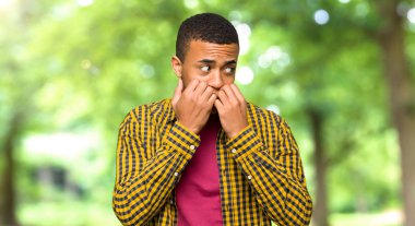 Biraz gergin ve korkmuş bir parkta ağız için ellerini koyarak genç afro Amerikalı adam