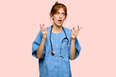 Pembe bir arka plan üzerinde kötü bir durum tarafından hayal kırıklığına uğramış genç redhead hemşire