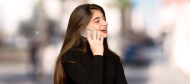 Güzel kız cep telefonu ile bir görüşme açık havada tutmak