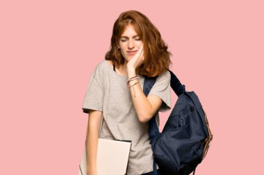 Pembe bir arka plan üzerinde diş ağrısı ile genç redhead öğrenci