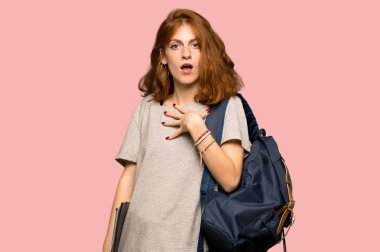 Şaşırttı ve şu pembe arka plan üzerinde bakarken şok genç redhead öğrenci