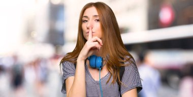 Kızıl saçlı öğrenci kadın parmak şehir ağzına koyarak sessizlik jest belirtisi gösteren