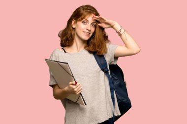 Pembe arka plan üzerinde el ile selamlayan genç redhead öğrenci