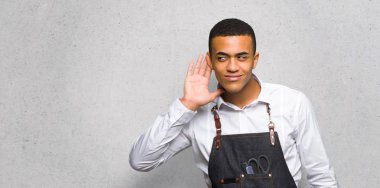 Genç afro Amerikan Kuaför adam için bir şey kulak dokulu duvar el koyarak dinleme