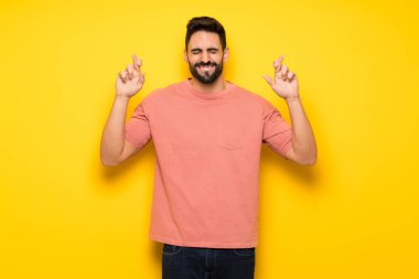 En iyi dilek ve geçiş parmaklarıyla sarı duvarın üzerinden yakışıklı adam