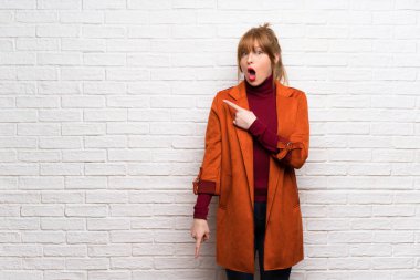 Kadın kat üzerinde beyaz tuğla ile şaşırmış ve işaret yan duvar