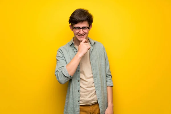 Adolescente Hombre Sobre Pared Amarilla Con Gafas Sonriendo — Foto de Stock