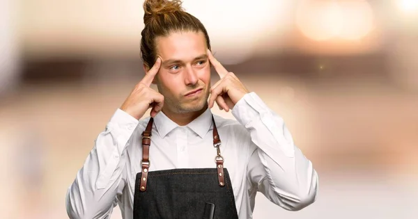 Barber man in an apron having doubts and thinking in a barber shop