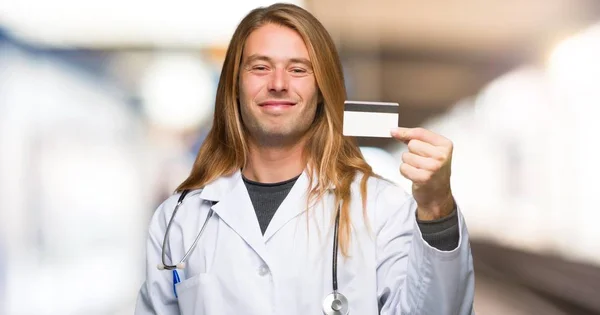 Doctor man holding a credit card in a hospital