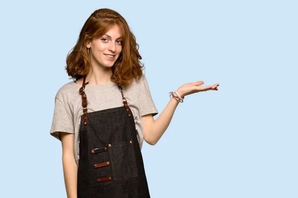 Young Redhead Woman Apron Holding Copyspace Imaginary Palm Insert Blue — Stock Photo, Image