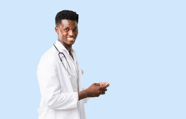 Африканский американский врач разговаривает с мобильным на изолированном синем фоне — стоковое фото