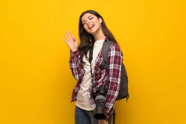 Fotógrafo Adolescente Chica Sobre Amarillo Pared Saludo Con Mano Con —  Fotos de Stock