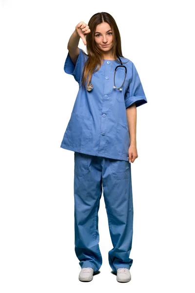 孤立した背景に親指で下を負の式と記号を示す全身若い看護師 — ストック写真